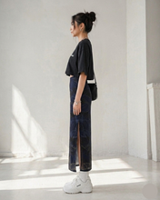 Load image into Gallery viewer, Person wearing a black crop top, a pencil skirt with a side slit, and white sneakers in a minimalistic setting.